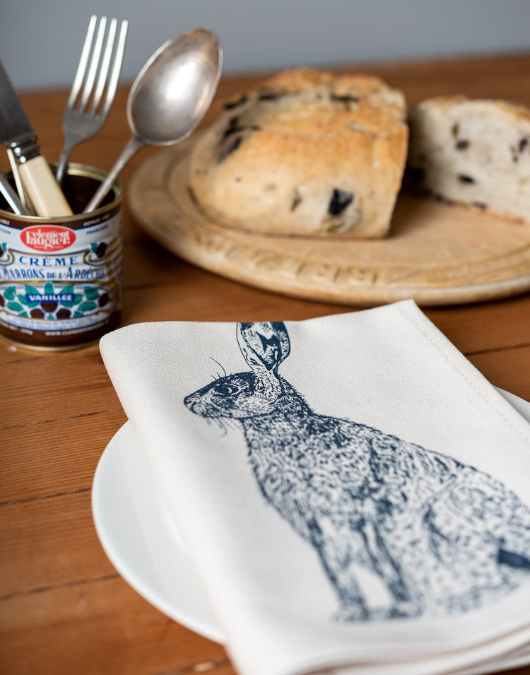 Lottie Day wildlife napkin set featuring handprinted hares and dahlias, styled on a rustic country table