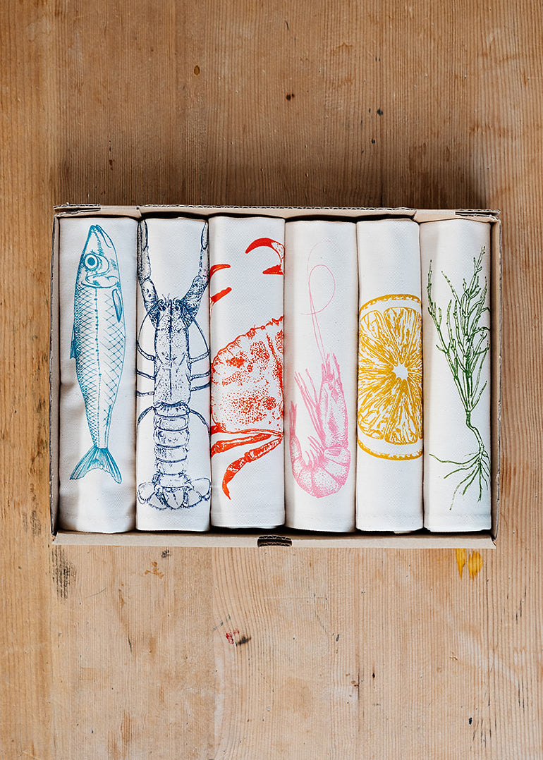 Seafood napkin gift set by Lottie Day featuring handprinted crab, blue lobster, prawn, mackerel, samphire and lemon illustrations on cotton napkins